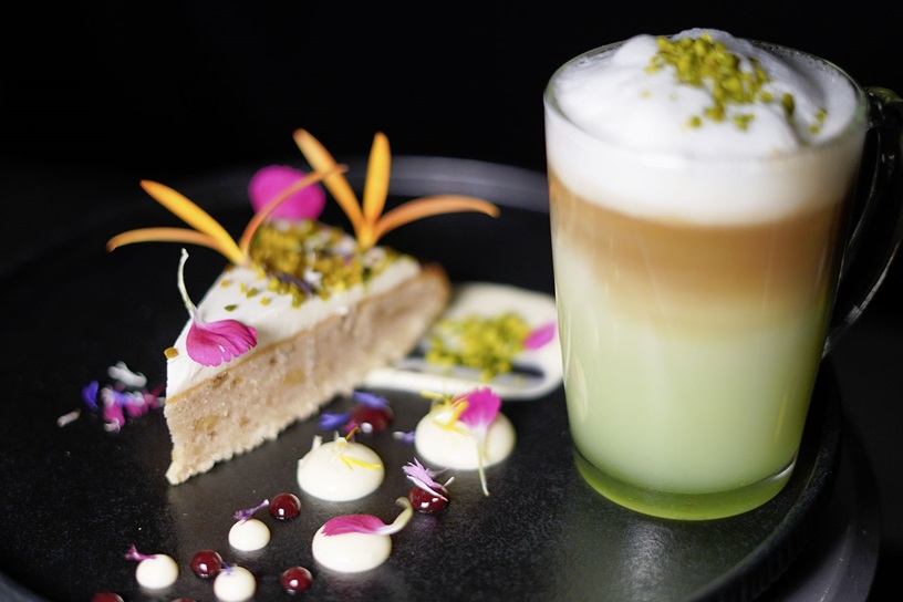 Banana Walnut Cake mit Pistazienkernen, frischen Blüten und trendiger Latte-Kombination